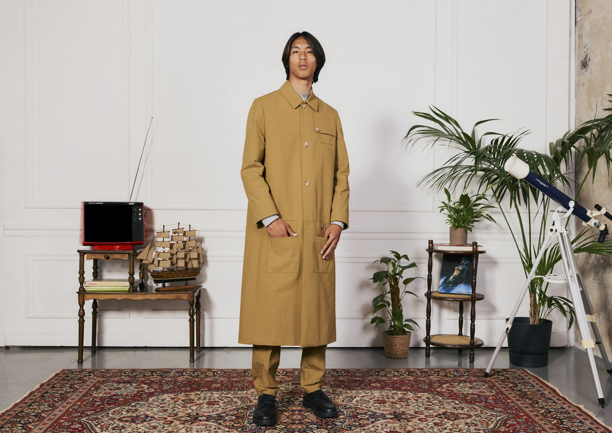 Homme en manteau long camel boutonné, de face, dans un intérieur clair