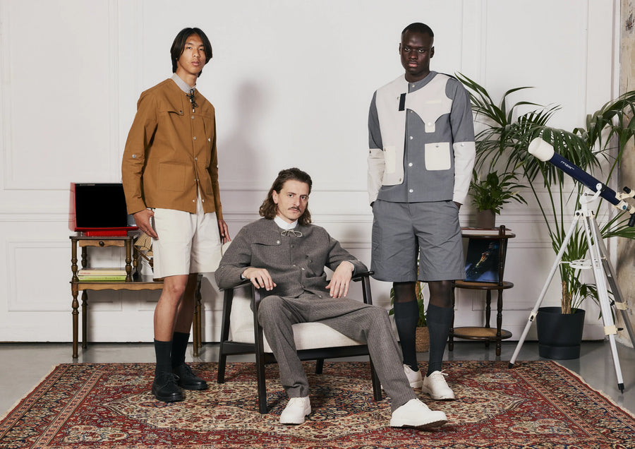 Trois hommes dans un salon : veste camel, ensemble gris, veste et short à empiècements