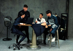 LA VESTE WORKER BLEUE EN COTON worn by a group of four young adults collaborating at a table.